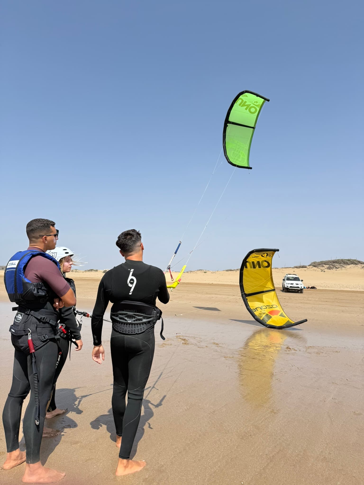 Kitesurf lessons Essaouira Morocco — IKO kite in the air, instructors in wetsuits on the beach